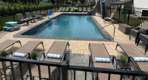 A swimming pool with lounge chairs and a slide, surrounded by a fence and potted plants. - Luxury 8BR Estate Heated Pool Walk to Shuls (Long Branch)