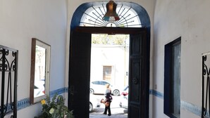 A hallway with a tiled floor, a hanging light fixture, and a door leading to an outdoor area. - Casa Roberto Hotel (Álamos)
