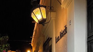 A narrow stone pathway leading to a building with a white facade and a black metal gate. - Casa Roberto Hotel (Álamos)