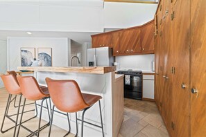 A modern kitchen with a wooden island, bar stools, and a built-in oven. - Luxury Resort Home | Golf, Ski & Lake Bellaire (Bellaire)