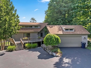 A two-story house with a garage, a covered porch, and a small garden area. - Luxury Resort Home | Golf, Ski & Lake Bellaire (Bellaire)