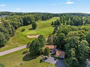 Luftaufnahme eines Golfplatzes mit Klubhaus und einer Straße.