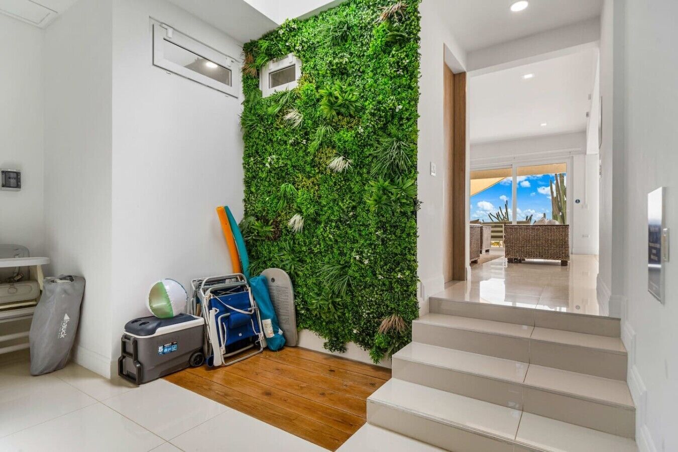 Ein modernes Interieur mit einer grünen Wand, einer Treppe und Blick ins Freie.