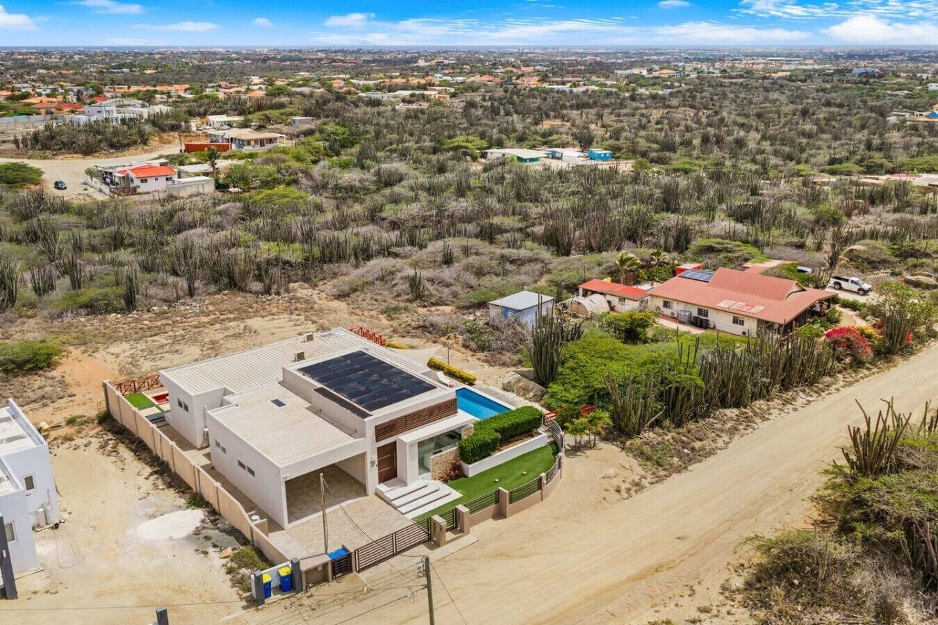 Una casa moderna con techo de paneles solares, piscina y vista a un paisaje desértico.