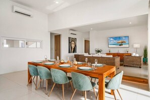 Un comedor moderno con una mesa de madera dispuesta para seis personas, rodeada de sillas color turquesa.