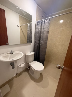 Et badeværelse med vask, toilet og bruseforhæng.