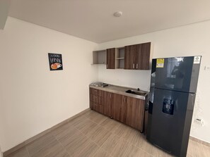 A kitchen with wooden cabinets, a stainless steel refrigerator, and a tiled floor.