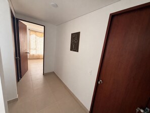 A hallway with a wooden door, a light switch, and a framed artwork on the wall.