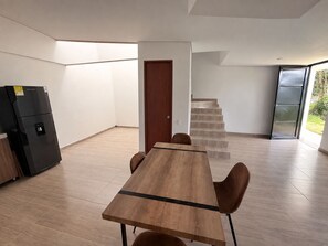 Et moderne køkken med et indbygget køleskab, et træspisebord med stole, og en trappe til en etage ovenpå.