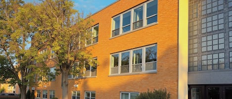 A multi-story building with a brick facade, large windows, and a well-maintained lawn.