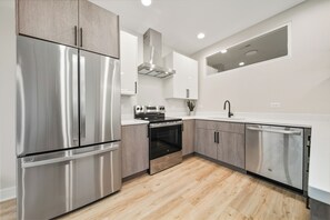 A modern kitchen with stainless steel appliances, wooden cabinets, and a white countertop.