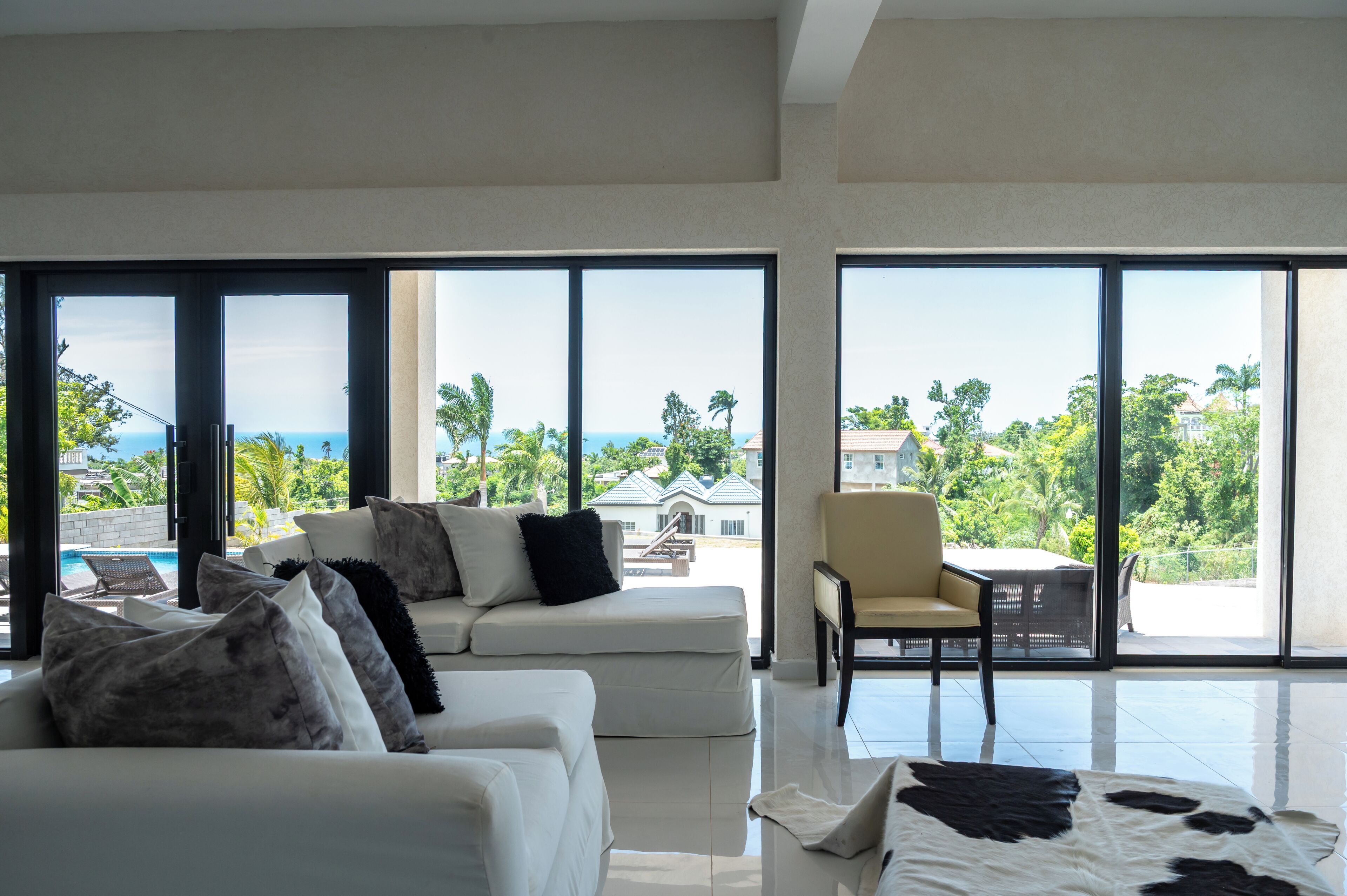 A spacious living room with a white sofa, a coffee table, and a view of the ocean through large windows.