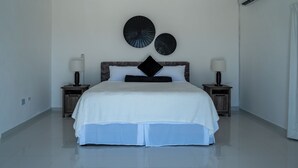 Une chambre moderne avec un grand lit, deux tables de chevet avec des lampes et des éléments de décoration circulaires fixés au mur.