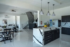 Una cocina moderna con una isla central, armarios negros y una encimera de mármol blanco.