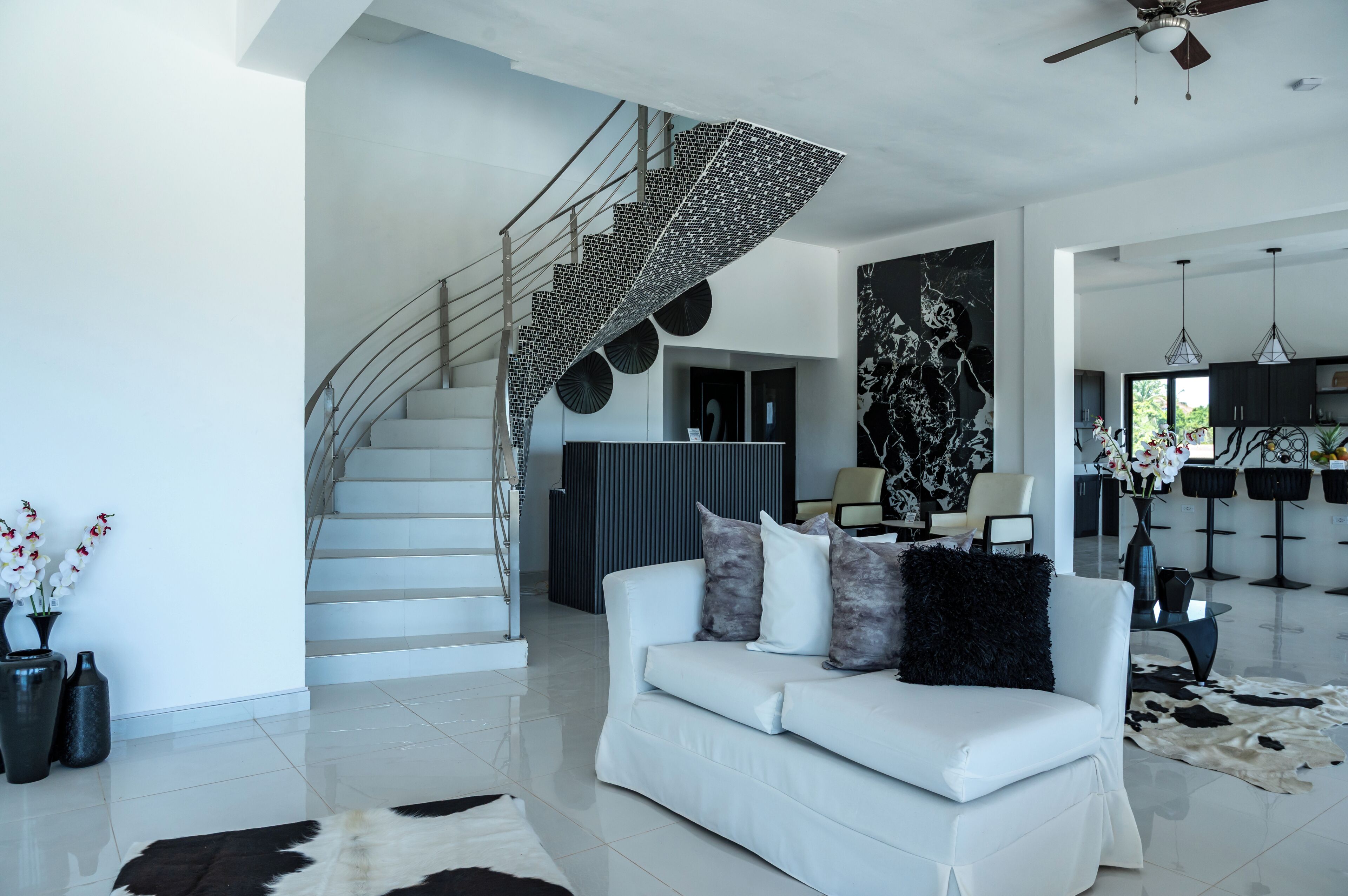 Ein modernes Interieur mit einer weißen Treppe, einem weißen Sofa und einem Cowhide-Teppich.