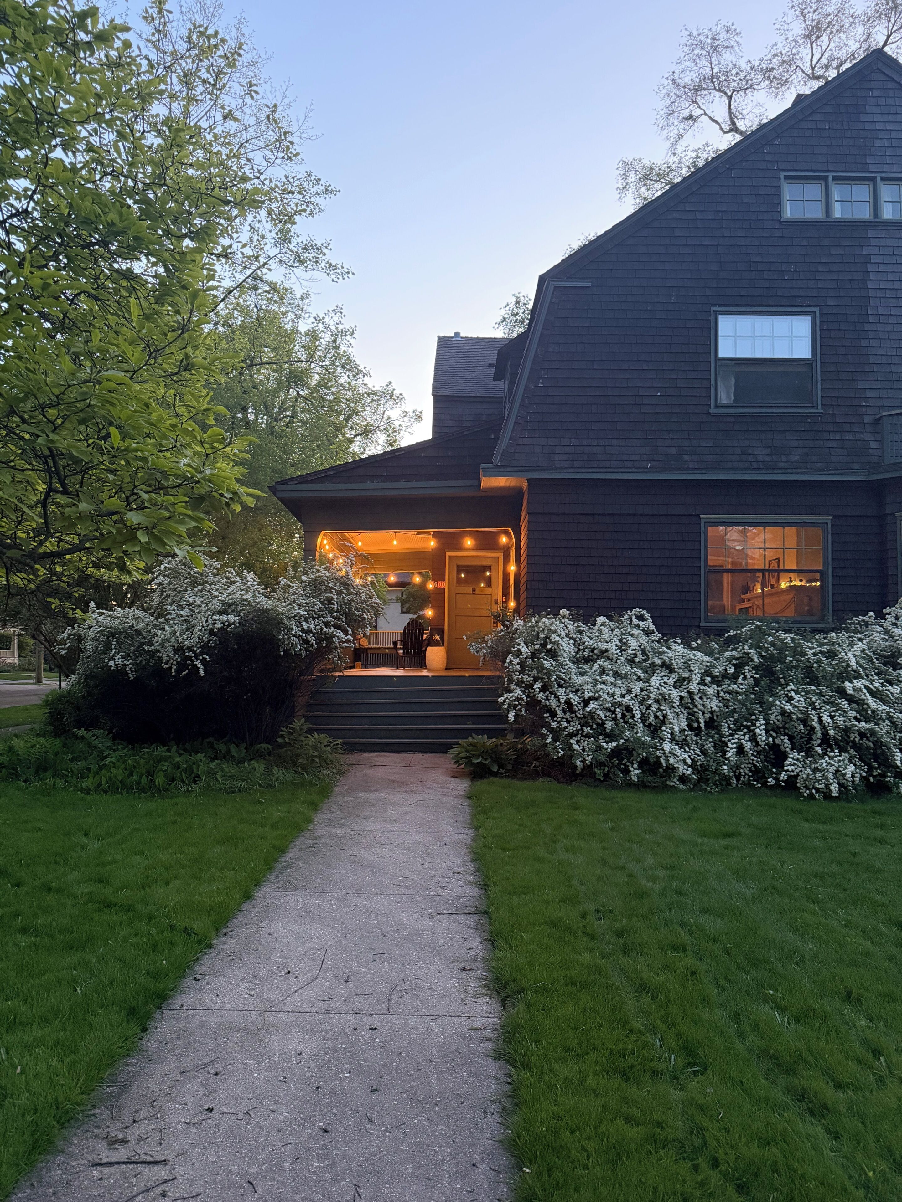 A two-story house with a front porch, a pathway leading to the entrance, and a well-maintained lawn.
