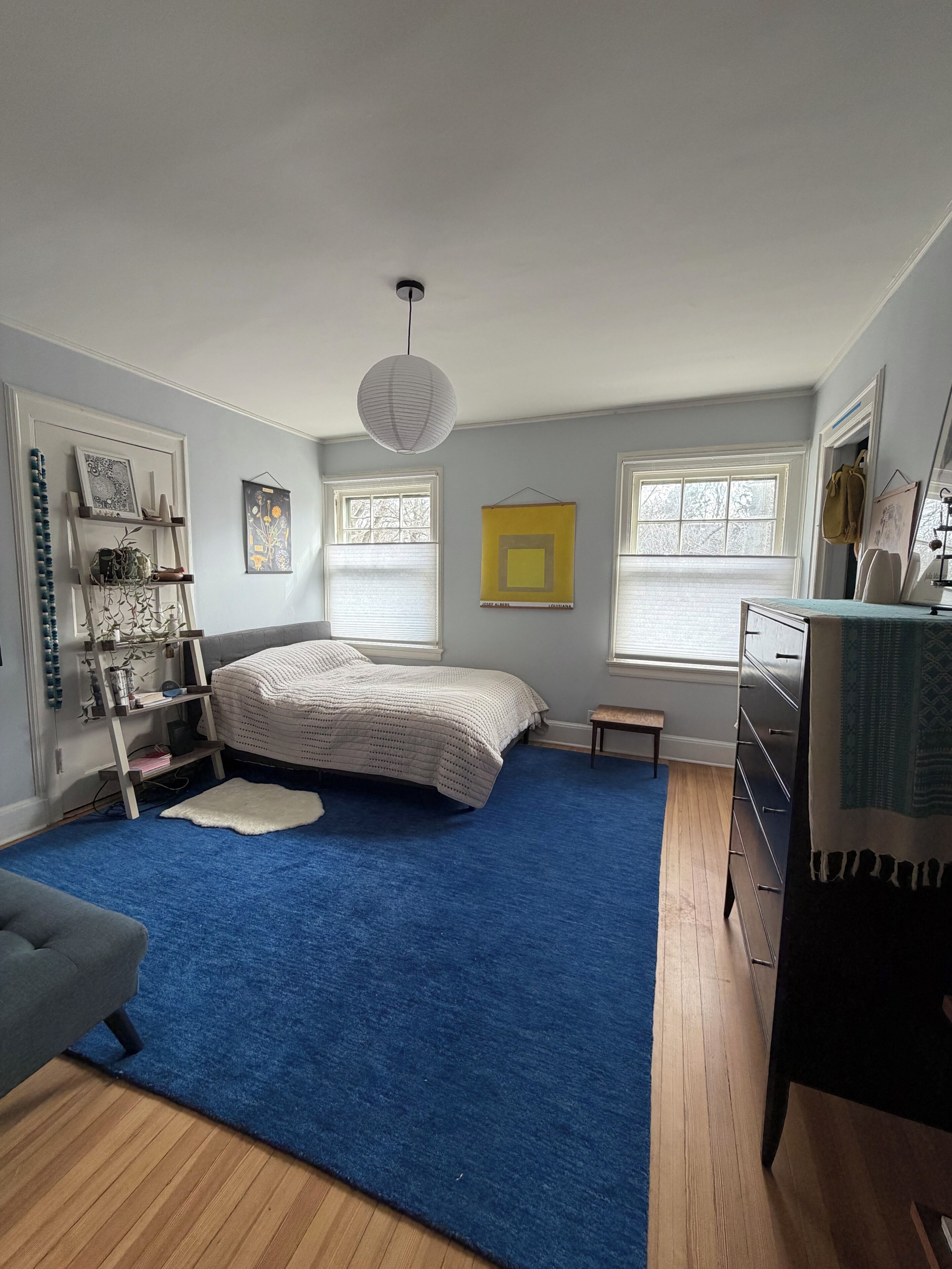 A bedroom with a bed, a dresser, a bookshelf, and a window.