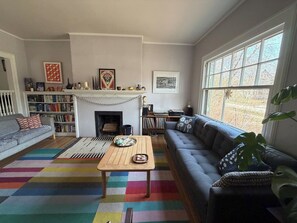 Una sala de estar con chimenea, estanterías, un sofá y un ventanal.