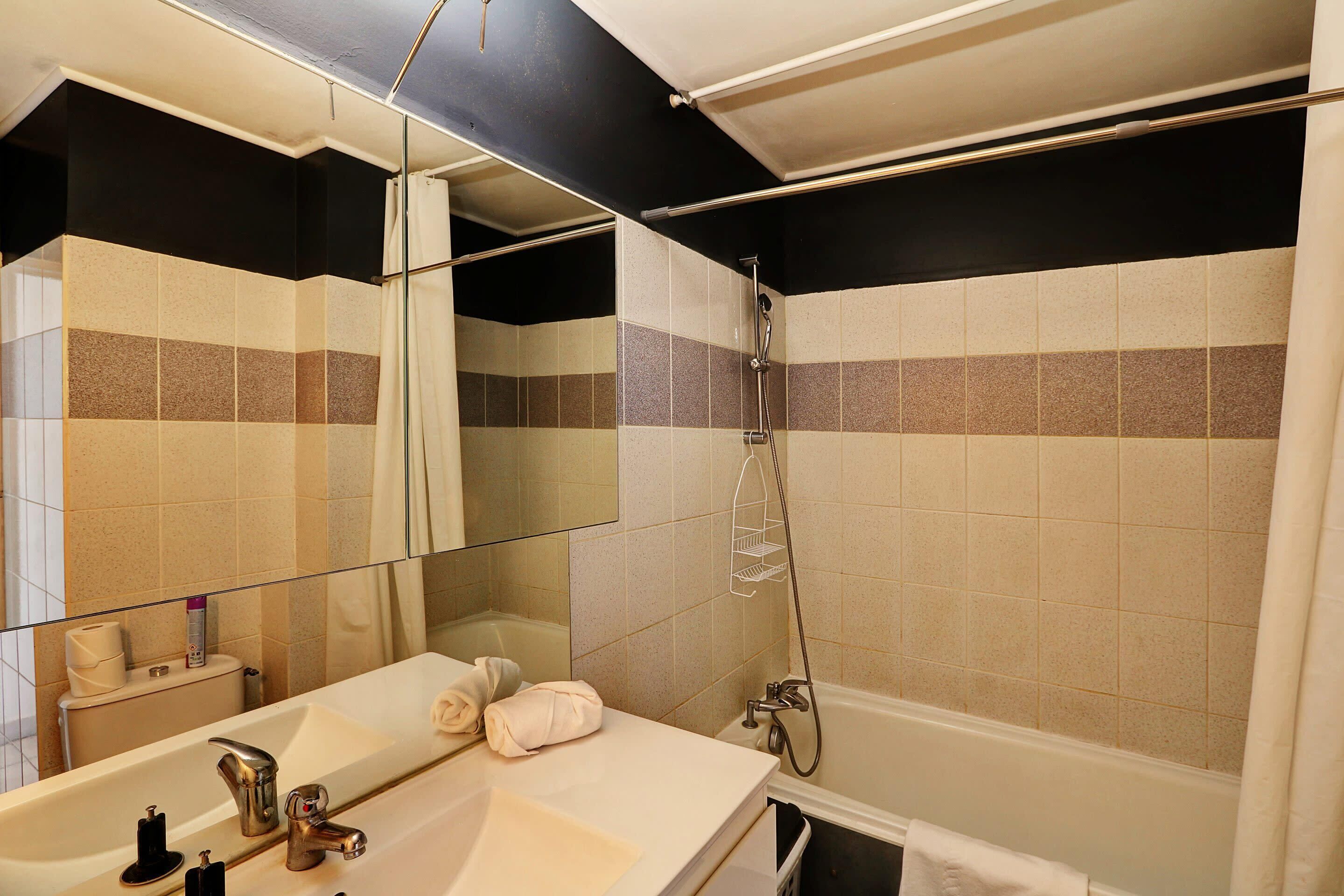 Ein Badezimmer mit einer Badewanne, einer Dusche, einem Waschbecken mit Spiegel und einem Handtuch.