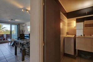 A modern interior with a dining area, a kitchen, and a balcony. - La Kaz Rouge - Climatisation - Plage (Saint-Paul)