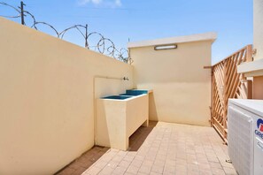 A small outdoor bathroom with a sink, a wooden fence, and a radiator. - Bon Bida Trupial, apartment with shared pool (Kralendijk)