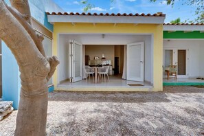 A building with a covered patio, a dining area with chairs and a table, and a door with the number 5. - Kas Kurá, garden terrace and pool in Kralendijk (Kralendijk)