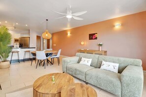 Ein modernes Wohnzimmer mit Sofa, Couchtisch, Essbereich und Deckenventilator.