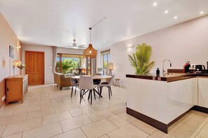 A modern kitchen with a central island, a dining area with a table and chairs, and a ceiling fan. - Bon Bida Blenchi, stylish apartment with pool (Kralendijk)