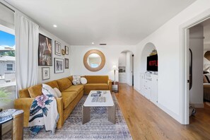 Una sala de estar moderna con un sofá, una mesa de centro y obras de arte en las paredes.