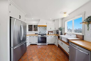 A modern kitchen with white cabinets, a stainless steel refrigerator, a stove, and a sink. - Golden Hill Escape Near Balboa Park & Zoo (San Diego)