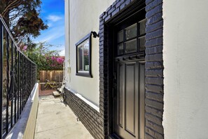 A narrow alleyway with a black door and windows, a wooden fence, and a bicycle. - Hot Tub & Arcade Escape Near Balboa Park (San Diego)