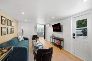 Ein modernes Wohnzimmer mit einem blauen Sofa, einem Couchtisch und einem an der Wand befestigten Fernseher.