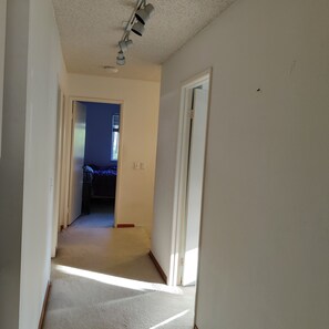 A hallway with a carpeted floor, a ceiling light fixture, and a door leading to another room. - Perfect two story home 4BR, 2.5 Bath in the heart of Rancho Penasquitos. (San Diego)