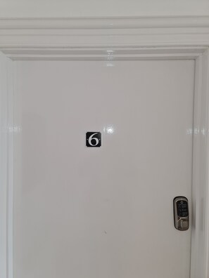 Eine weiße Tür mit einem Aufkleber mit der Zahl 6 und einem Klingel.