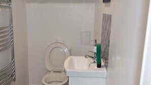 Um banheiro pequeno com vaso sanitário, pia e porta-toalhas.