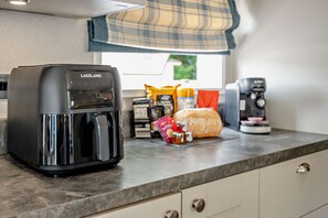 A kitchen with a coffee maker, a toaster, and various food items on the counter. - Kernow Lodge Luxe Seaside Cabin Wraparound Deck (Milford on Sea)
