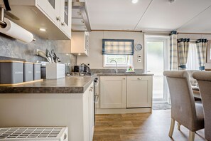 Eine moderne Küche mit Kochinsel, eingebauten Schränken und einem Fenster mit Vorhängen.