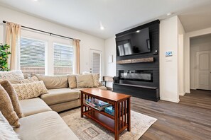 Een woonkamer met een bank, een salontafel, een open haard en een televisie.