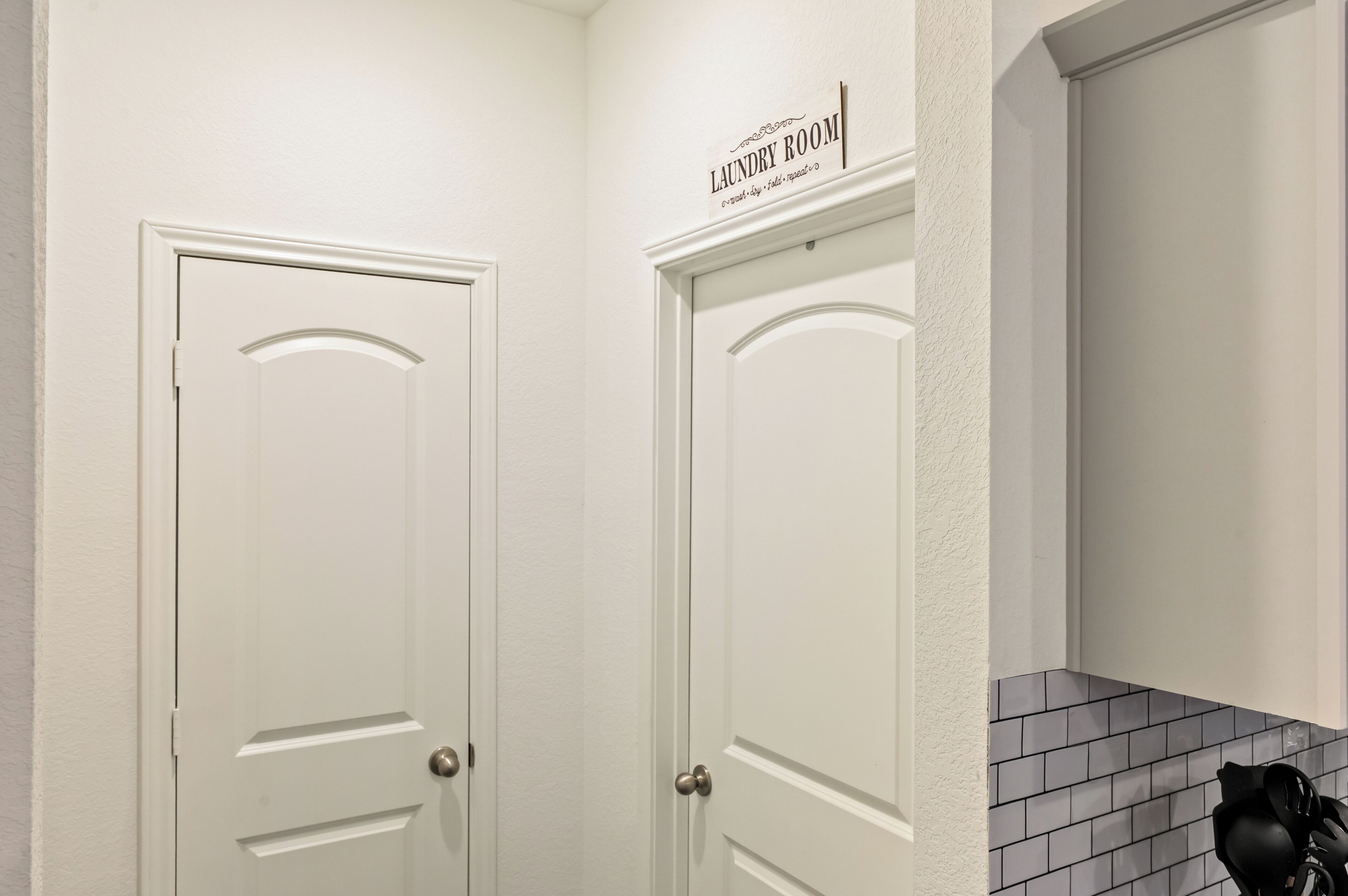 Een hoek van een kamer met twee witte deuren, waarvan één 'Laundry Room' is met instructies voor wastaken.