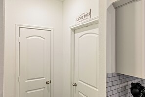 Et hjørne af et rum med to hvide døre, hvoraf den ene er mærket 'Laundry Room' med vejledning til vasketøj.