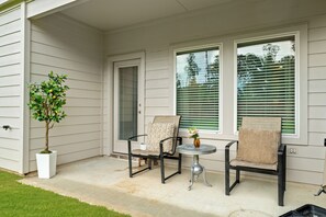A covered porch with two chairs and a small table, a potted plant, and a door with a window. - Spacious 5-bedroom Family House in Spring near George Bush Airport (Spring)