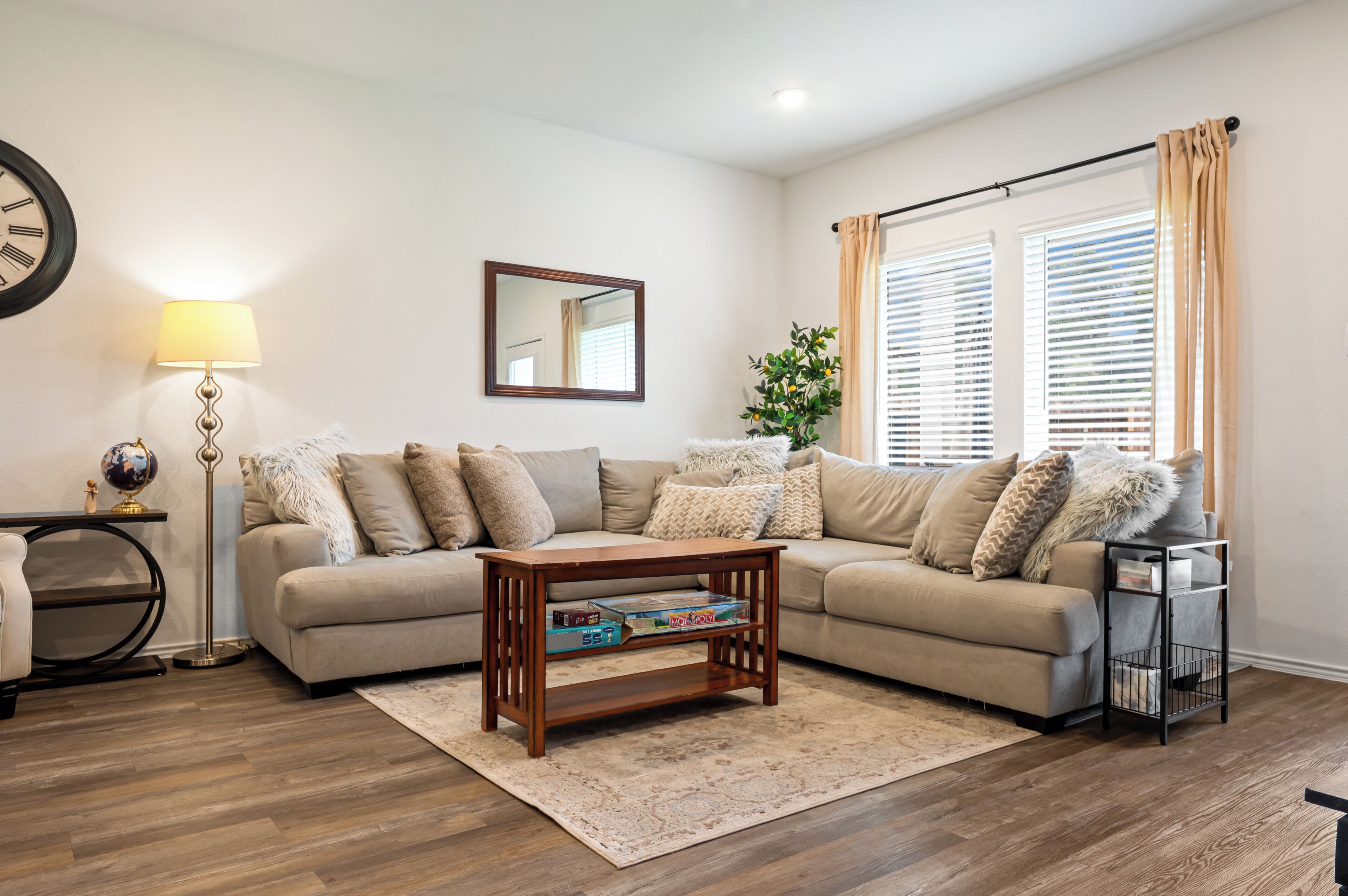 A living room with a sofa, a coffee table, a lamp, a globe, and a mirror.