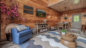 A cozy room with a blue sofa, wooden walls, a television, and a coffee sign.