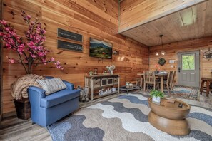 A cozy room with a blue sofa, wooden walls, a television, and a coffee sign.