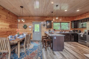 L’intérieur d’une cabane en bois comprend un coin repas, une cuisine et une grande fenêtre.