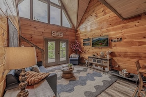 Ein gemütliches Blockhaus-Interieur mit Treppe, einer Couch, einem Couchtisch und einem Kamin.