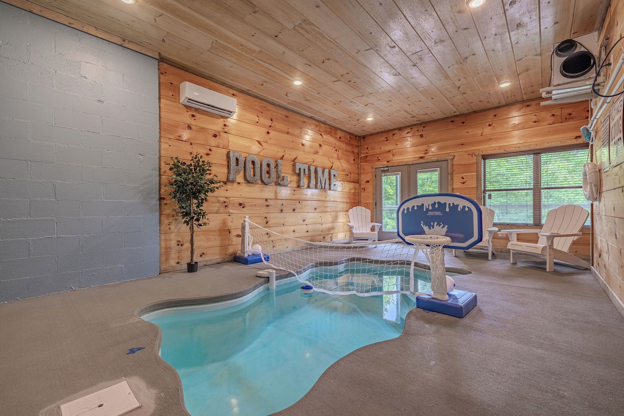 A pool area with a wooden interior, a basketball hoop, and Adirondack chairs.