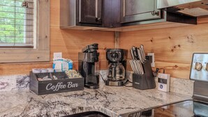Ett kök med en kaffestation som inkluderar en kaffebryggare, en kaffekvarn och ett knivblock.