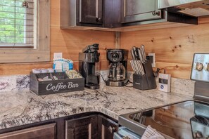 Eine Küche mit einer Kaffeebar, inklusive Kaffeemaschine, Kaffeemühle und Messerblock.