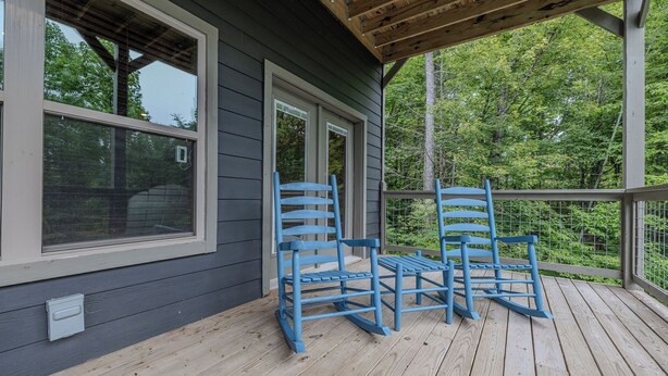 A wooden deck with two rocking chairs and a covered porch area.